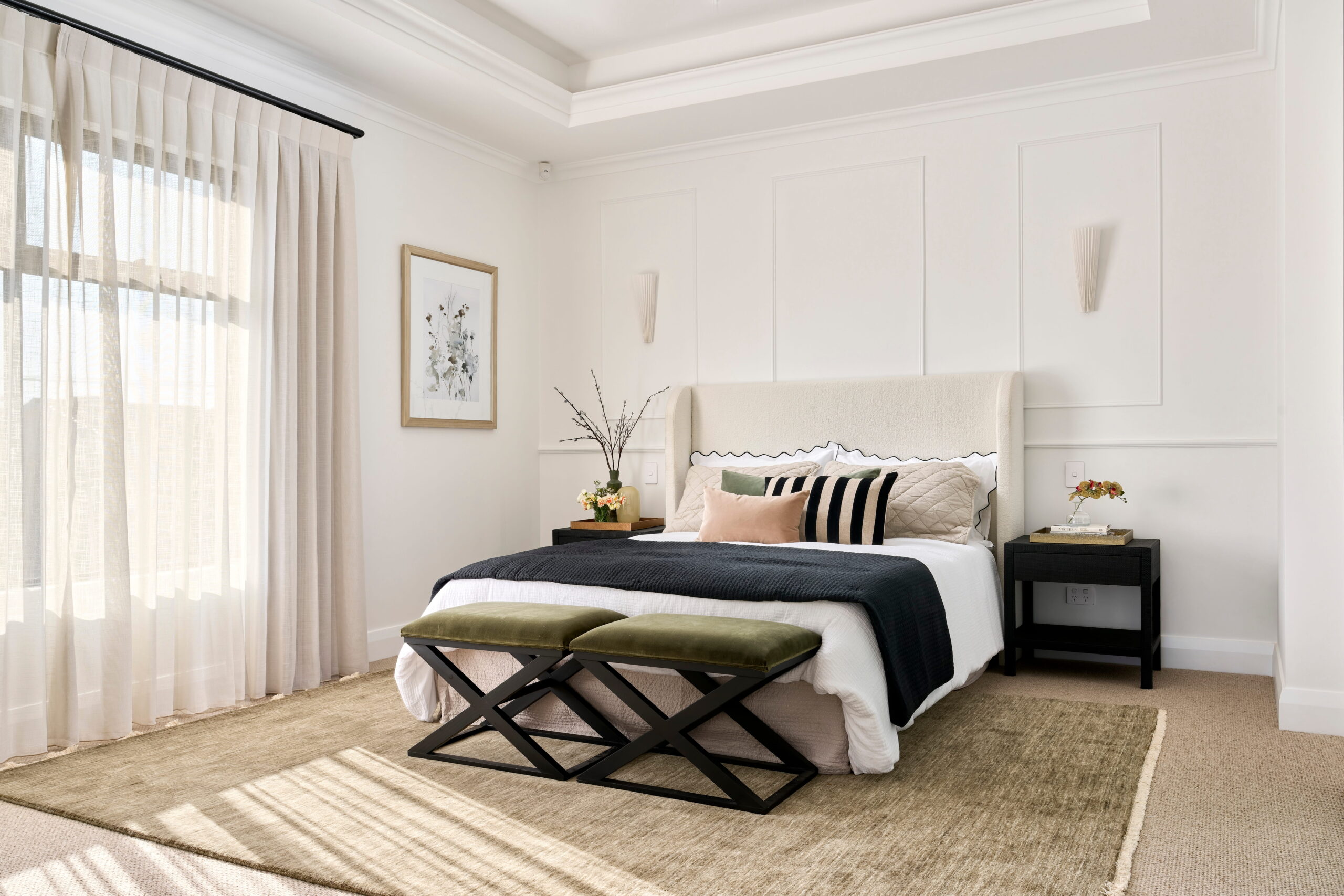 Bedroom with panelled feature wall, tray ceiling, upholstered bedhead and olive velvet bench stools in a custom Perth home.