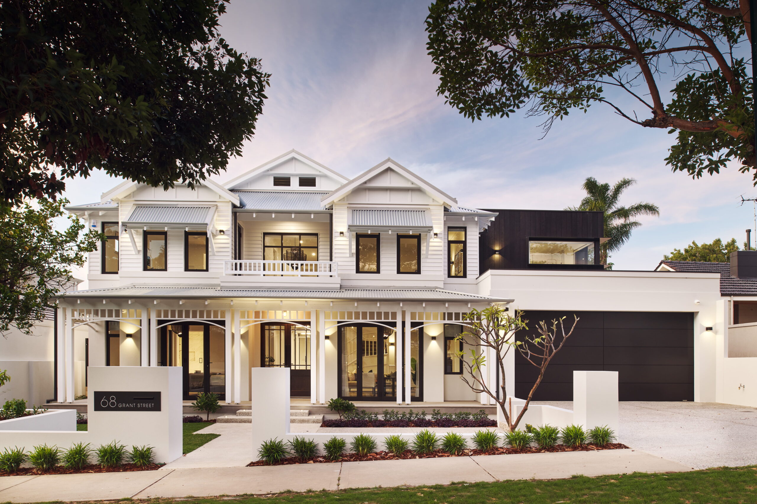 Two-storey custom home in Perth with white Hamptons-style facade, wraparound verandah, black-framed windows and double garage.