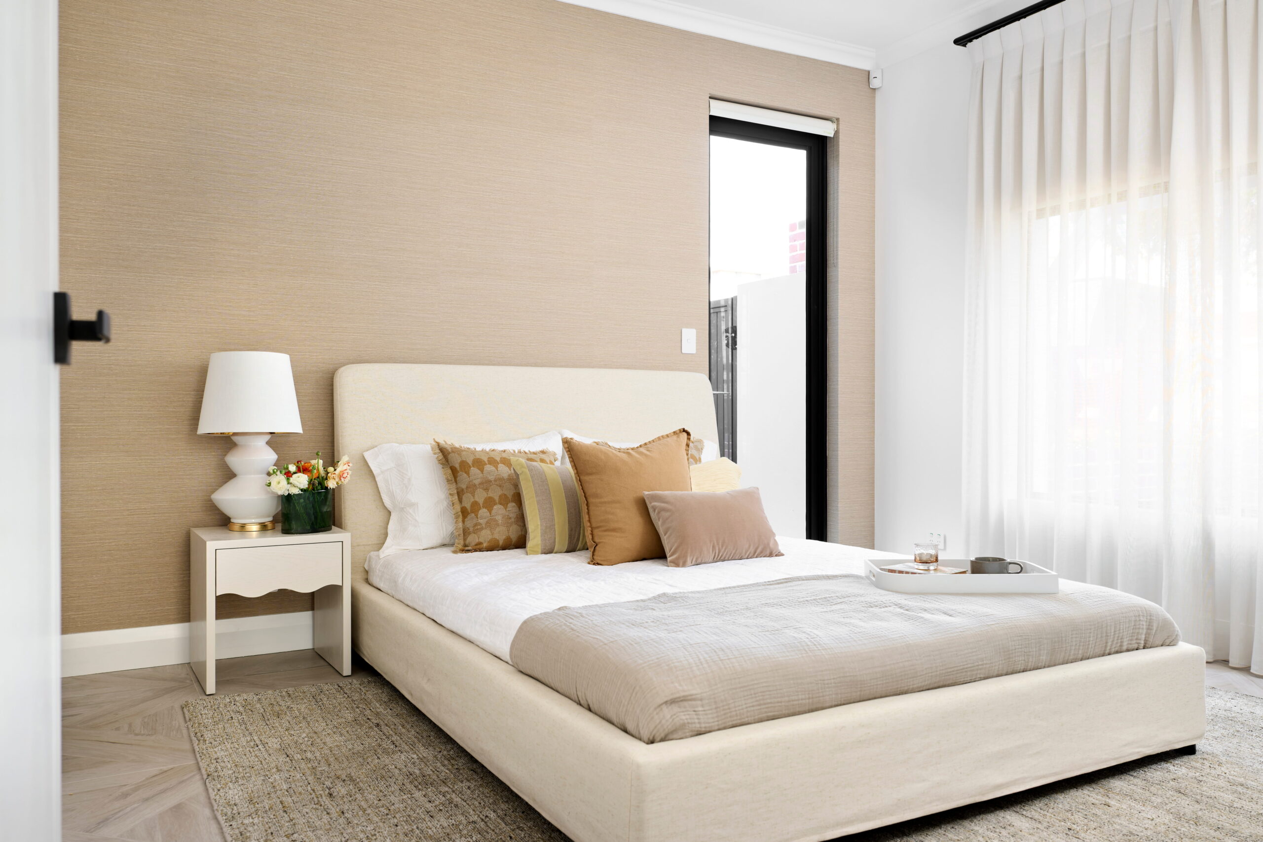 Bedroom in a custom Perth home with textured grasscloth wallpaper, upholstered bedhead and herringbone timber flooring.