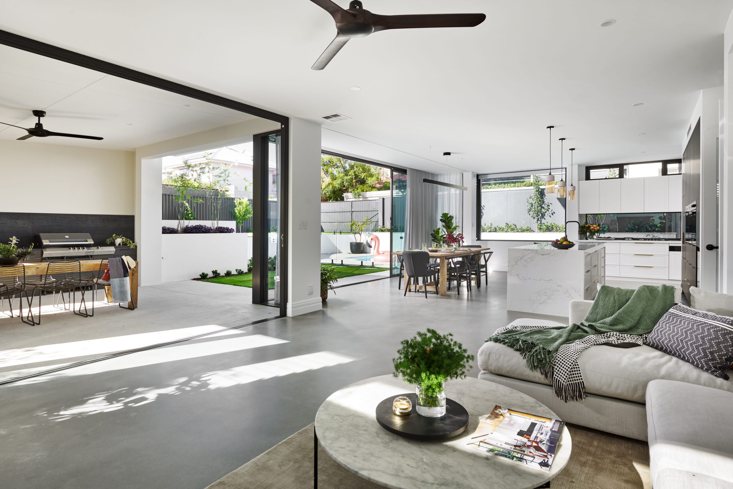 North-facing open-plan living area with stacker doors opening to alfresco and pool