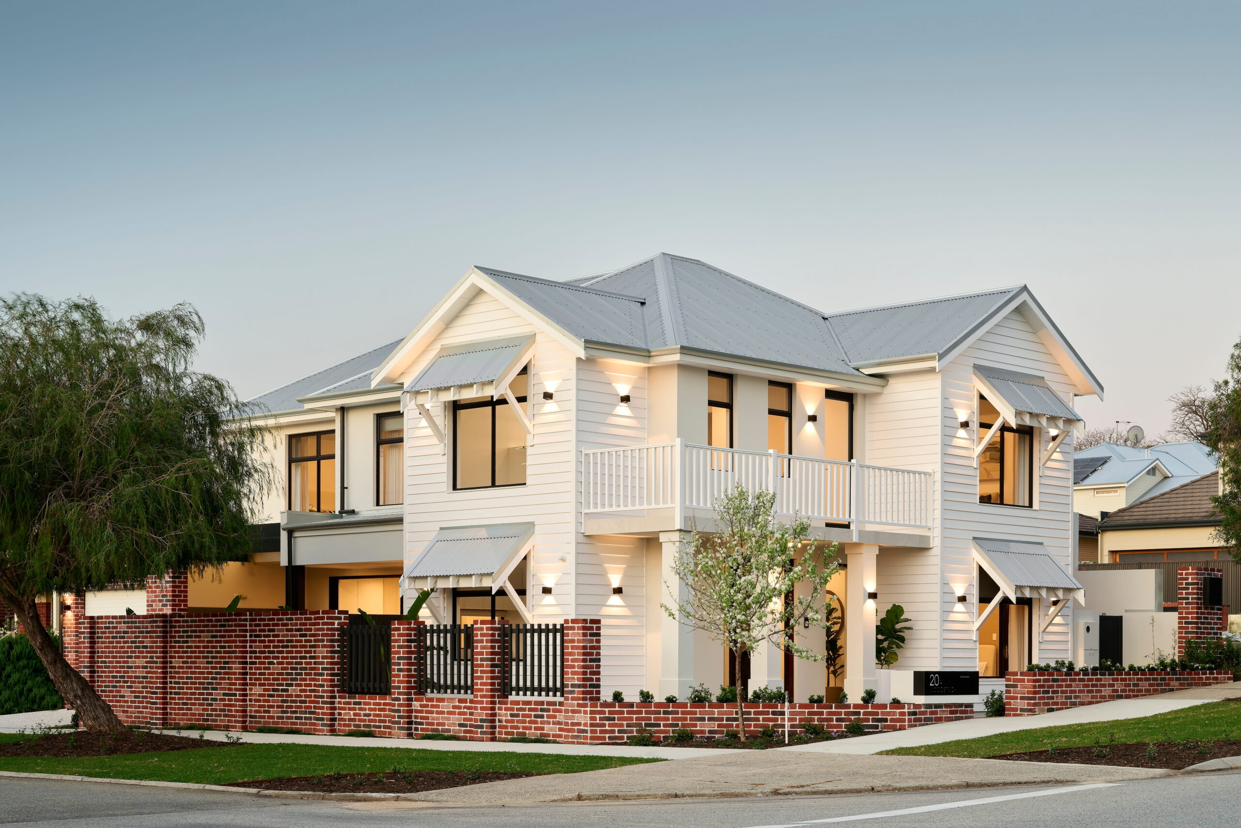 Two-storey custom home built by Stannard Homes in Perth, with white weatherboard and red brick exterior with balcony and landscaped frontage
